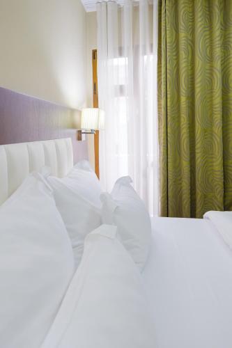 a bedroom with two white beds and a window at Hotel Pietroasa in Buzau