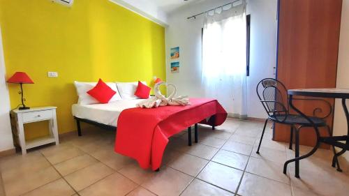 Schlafzimmer mit einem Bett mit einer roten Decke und einem Tisch in der Unterkunft B&B Demarete sullo Ionio in Arenella