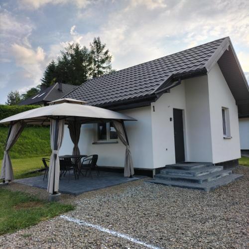 a white house with a table and an umbrella at Bieszczadzki Orzeł in Berezka