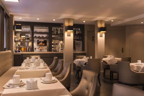 un restaurant avec des tables et des chaises blanches et un bar dans l'établissement La Villa des Ternes, à Paris