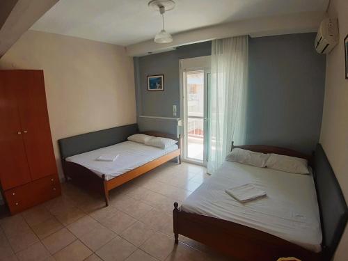 1 dormitorio con 2 camas y una ventana con puerta en Villa Metaxa, en Paralia Katerinis
