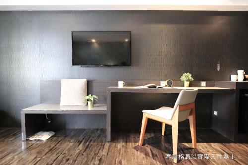 a desk with a chair and a television on a wall at Talmud Hotel Yizhong in Taichung