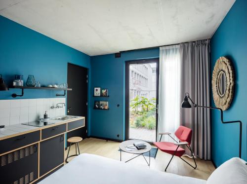 sypialnia z niebieskimi ścianami, umywalką i 2 krzesłami w obiekcie Deskopolitan House w Paryżu