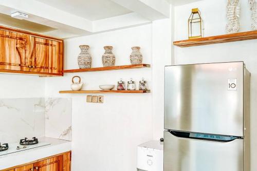 a kitchen with a stainless steel refrigerator and wooden cabinets at Mytongos Private Villa in Nusa Lembongan