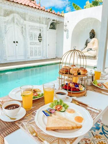 a table with breakfast foods and drinks on a table next to a pool at Mytongos Private Villa in Nusa Lembongan