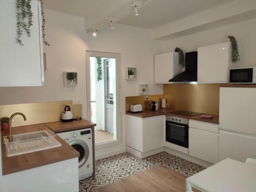 cocina con armarios blancos, lavadora y secadora en Les Loges de Montauban, en Montauban