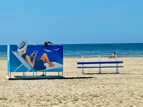 a sign on the beach with a woman sitting in a beach chair at Villa Blue Heaven Pärnu in Pärnu