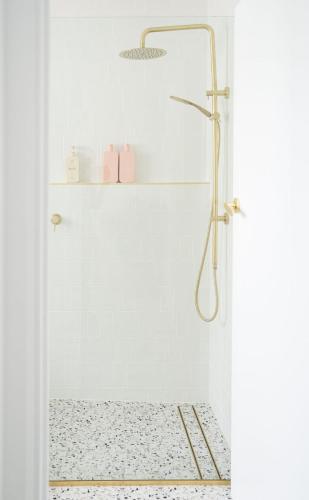 a white bathroom with a shower with a gold shower head at Luxury hideaway holiday unit in CBD in Mount Gambier