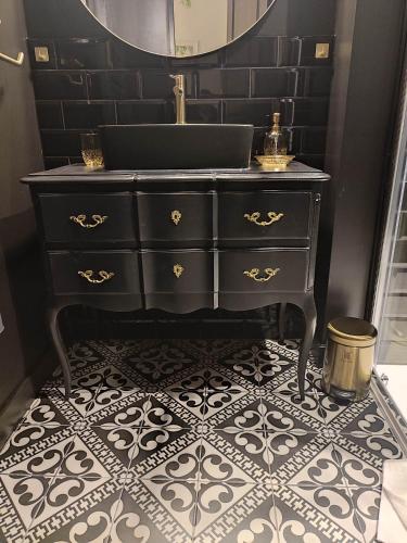 La salle de bains est pourvue d'une commode noire et d'un miroir. dans l'établissement Les Loges de Montauban, à Montauban