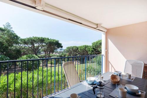 une table et des chaises sur un balcon avec une grande fenêtre dans l'établissement Bright cocoon with pool and sea view, à Sainte-Maxime