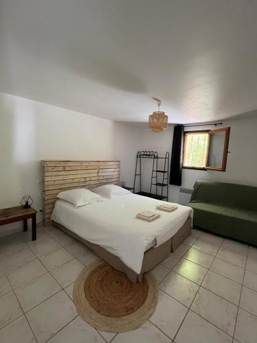 1 dormitorio con 1 cama grande y 1 sofá verde en Le Pavillon de Nina, en Puget