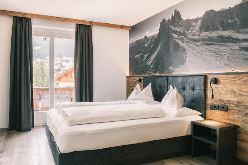 a bedroom with a large bed and a large window at Kristiania Small Dolomites Hotel in Selva di Val Gardena