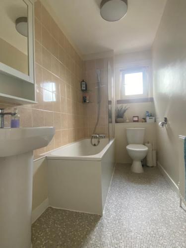 a bathroom with a tub and a toilet and a sink at Cozy bedroom in shared accommodation with free parking in Edinburgh