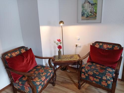 a living room with two chairs and a table with a lamp at Ferienwohnung Sauerland Burgfenster in Lennestadt