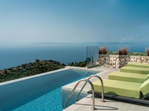 uma piscina com espreguiçadeiras verdes ao lado de uma piscina em Anadeo Villas & Suites em Exanthia