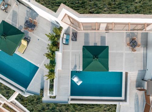 an overhead view of a swimming pool with green umbrellas at Anadeo Villas & Suites in Exanthia