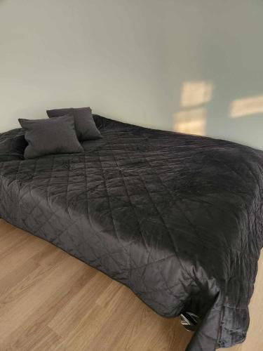 a large black bed sitting on a wooden floor at Prie Vilneles Apartment in Vilnius
