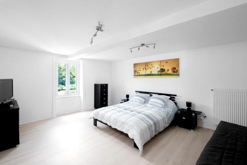 a white bedroom with a bed and a painting on the wall at Le Verdier - Charmante maison pour 10 avec jardin in Peschadoires