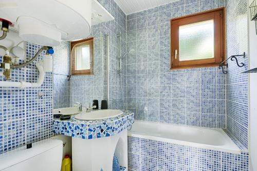 baño de azulejos azules con lavabo y bañera en Les Sapins du Tholy - Appt vue montagne, en Le Tholy