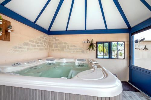 a jacuzzi tub in a room with blue ceilings at Villa Boyard - Pour 10 avec piscine privée et jacuzzi in Saint-Nazaire-sur-Charente