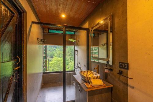 a bathroom with a sink and a shower with a window at Dharamalaya by StayVista - The Eco Home in Dharamshala