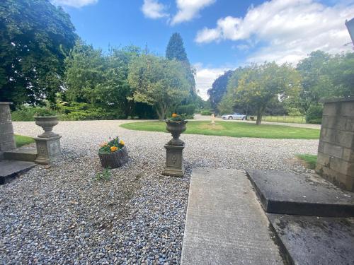 a garden with two vases with flowers on a gravel road at Bellfield Country Suites in Masham