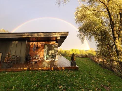 a house with a rainbow in the background at Landscape, New Eco Lodge Flatford Mill in East Bergholt