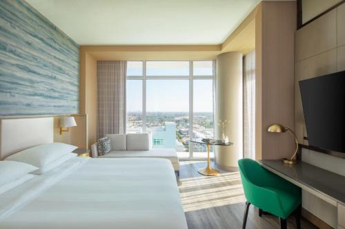 デイニア・ビーチにあるMarriott Fort Lauderdale Airportのベッドと大きな窓が備わるホテルルームです。