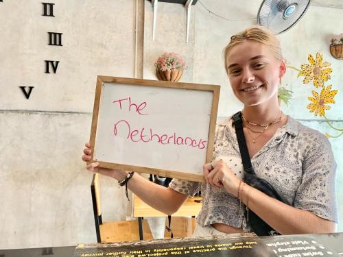 a woman holding a sign that says the refrigerator at Doze Hostel in Chiang Mai
