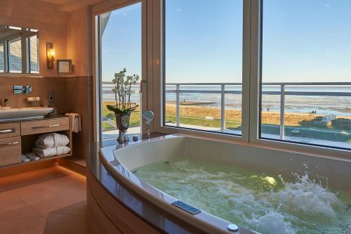 a bathroom with a tub with a view of the ocean at Badhotel Sternhagen in Cuxhaven