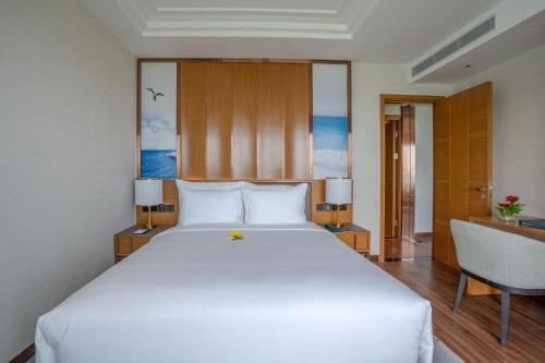 a bedroom with a large white bed and a desk at Grand Hyams Hotel - Quy Nhon Beach in Quy Nhon