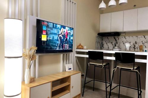 a kitchen with a bar with stools and a flat screen tv at Cozy Condo in San Jose Del Monte Bulacan Loft 2109 in Tunkong Manga