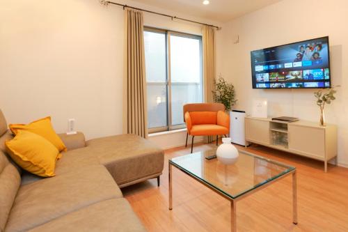 a living room with a couch and a chair and a tv at ACOE HATSUDAI - 4BR Entire Home Upscale Area in Tokyo