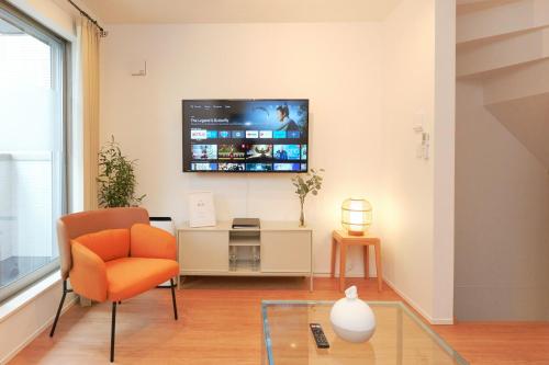 a living room with a chair and a tv on the wall at Shinjuku 1 Sta.・98㎡・4BR Entire Home Upscale Area in Tokyo