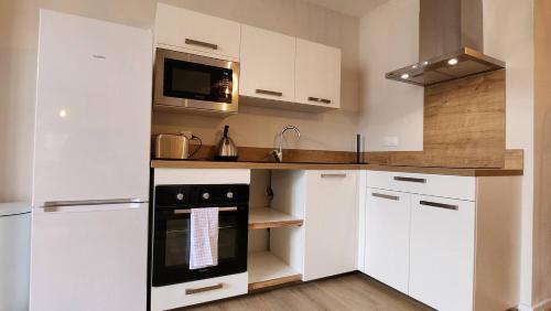 eine Küche mit weißen Schränken und einem schwarzen Gerät in der Unterkunft Les appartements de Louis in Limoges
