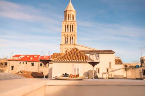 a table with two glasses of wine and a plate of food at Slavija Culture Heritage Hotel in Split