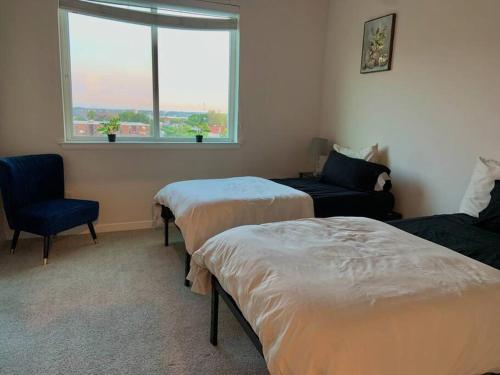 een kamer met 2 bedden, een stoel en een raam bij Contemporary Cozy Apartment in Baltimore