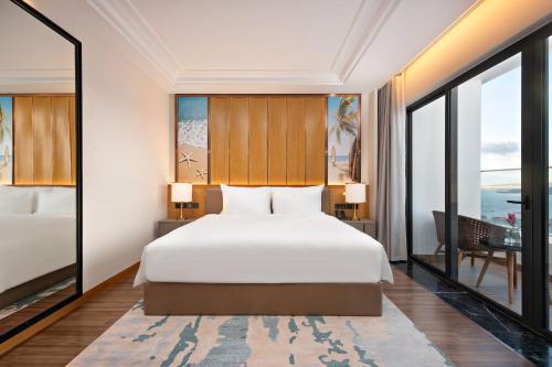 a bedroom with a bed and a view of the ocean at Grand Hyams Hotel - Quy Nhon Beach in Quy Nhon