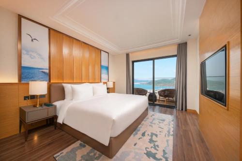 a bedroom with a large white bed and large windows at Grand Hyams Hotel - Quy Nhon Beach in Quy Nhon