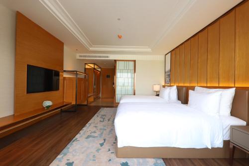a hotel room with two beds and a flat screen tv at Grand Hyams Hotel - Quy Nhon Beach in Quy Nhon