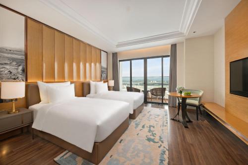 a hotel room with two beds and a television at Grand Hyams Hotel - Quy Nhon Beach in Quy Nhon