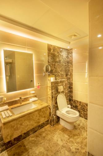a bathroom with a toilet and a sink and a mirror at Sparrow Apartments Hotel in Jeddah