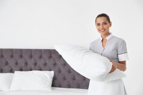 a woman standing next to a bed holding a pillow at Executive Apartment’s Mk in Milton Keynes