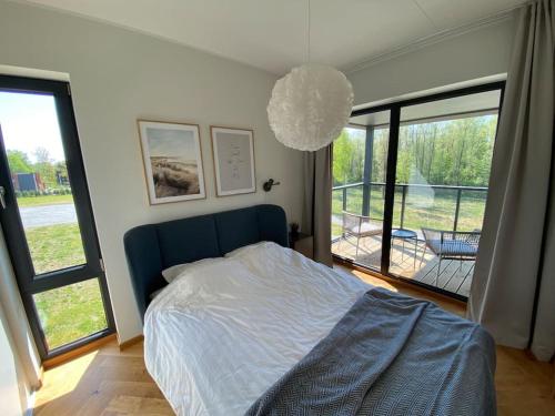 Schlafzimmer mit einem Bett mit blauem Kopfteil und Fenstern in der Unterkunft Cozy apartment near the beach and the city center in Tartu