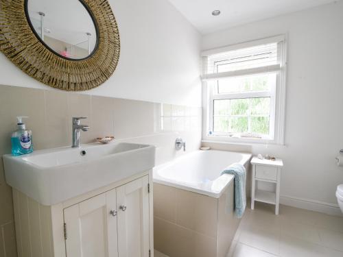 a white bathroom with a sink and a mirror at River Lym Cottage in Lyme Regis
