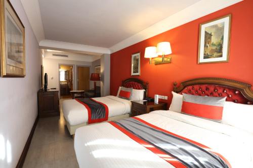 a hotel room with two beds and orange walls at Hôtel Les Saisons in Casablanca
