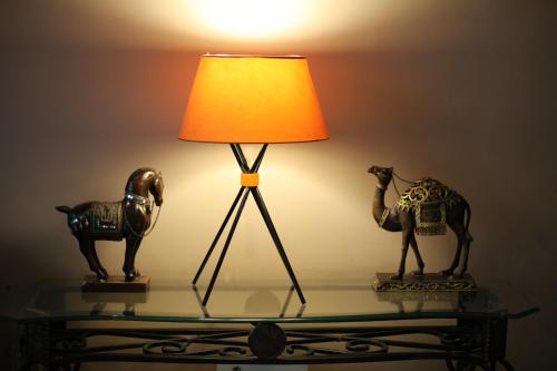 a lamp on a glass table with two statues of a camel at Hôtel Les Saisons in Casablanca