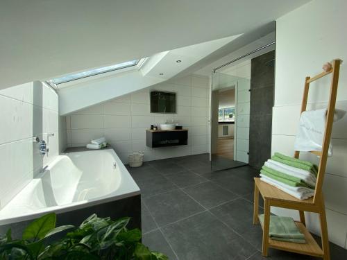 ein Badezimmer mit einer Badewanne, einem Waschbecken und einem Stuhl in der Unterkunft Alpenland Apartments in Aschau im Chiemgau