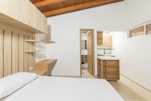 a bedroom with a white bed and a kitchen at Discover urban life in the heart of Medellin 202 in Medellín