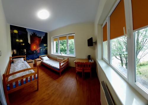a bedroom with a bed and a couch and windows at Szkolne Schronisko Mlodziezowe w Olsztynie in Olsztyn